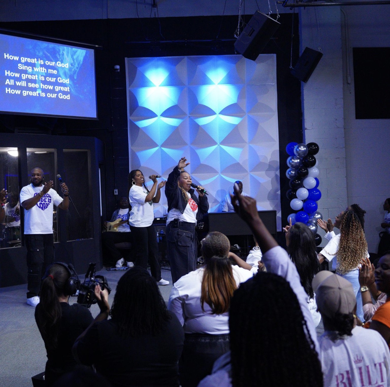 The worship team leading on stage beneath blue lights