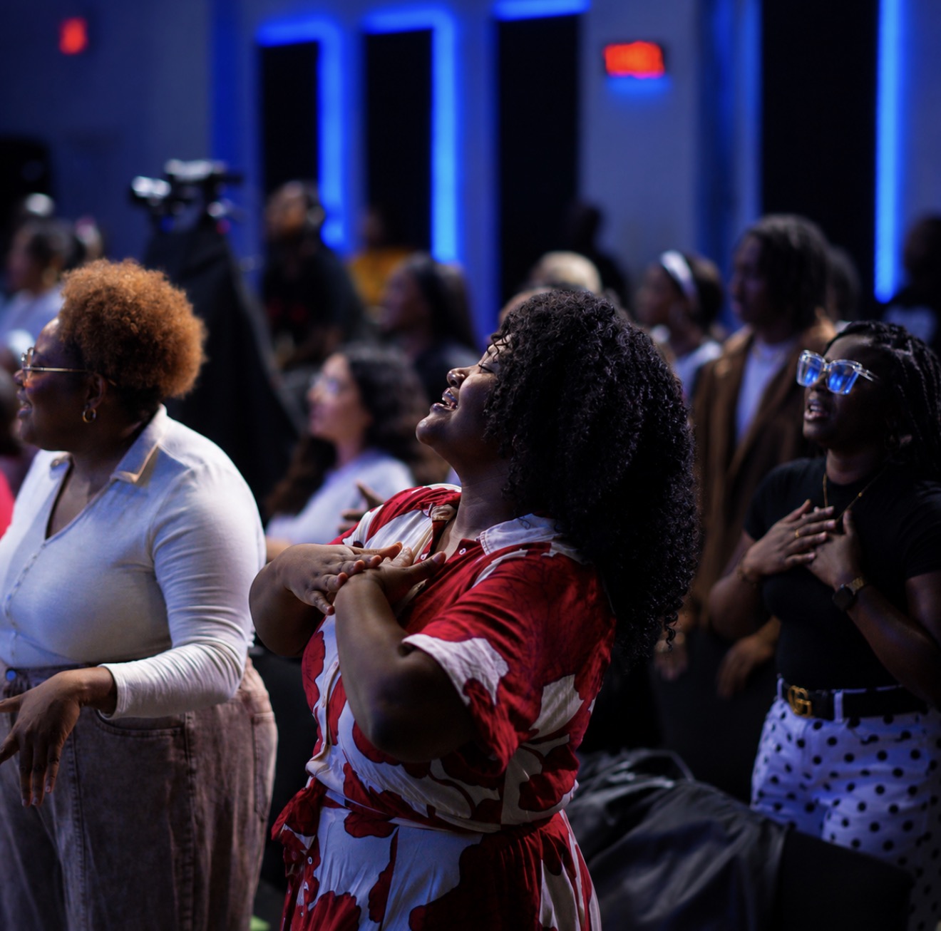 A woman worshipping with joy, eyes closed, hands on heart